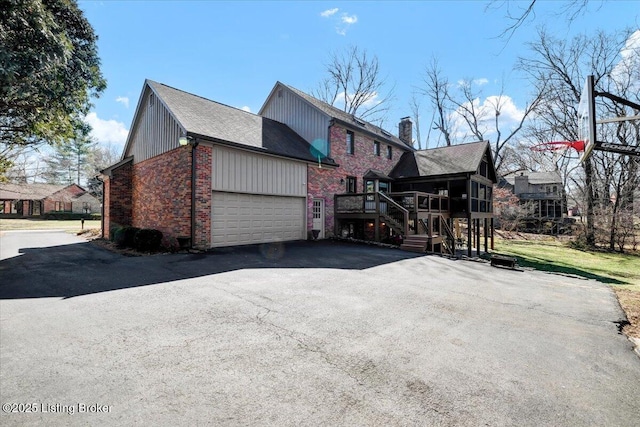 view of side of property with a garage, brick siding, driveway, and a chimney