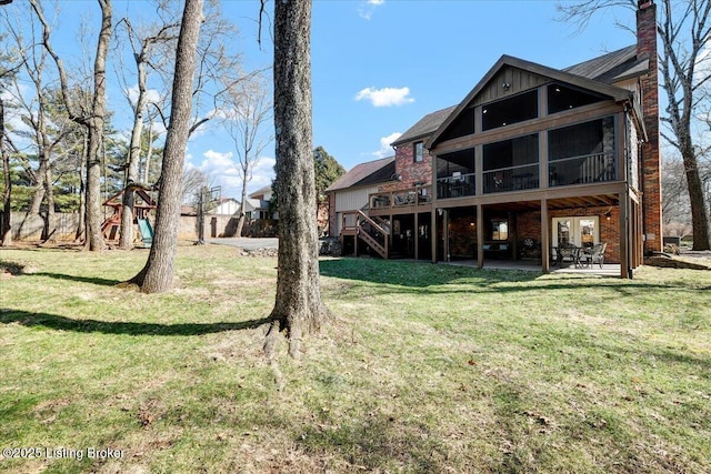 back of property featuring a lawn, board and batten siding, a sunroom, a patio area, and stairs