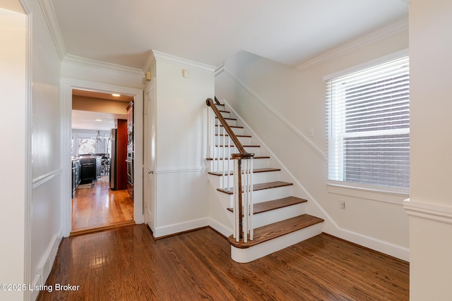 staircase featuring baseboards, wood finished floors, and crown molding