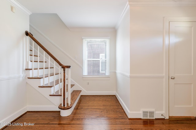 staircase featuring ornamental molding, wood finished floors, visible vents, and baseboards