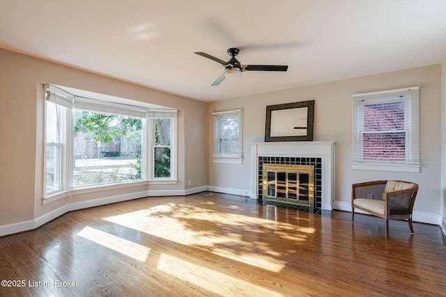 sitting room featuring a ceiling fan, baseboards, wood finished floors, and a tile fireplace