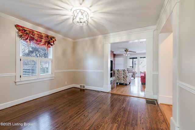 spare room with baseboards, wood finished floors, visible vents, and crown molding