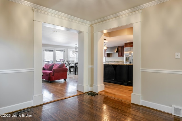 interior space featuring visible vents, an inviting chandelier, ornamental molding, wood finished floors, and baseboards