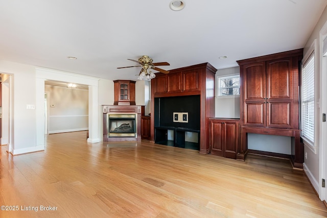 unfurnished living room featuring ceiling fan, recessed lighting, a fireplace, baseboards, and light wood-type flooring