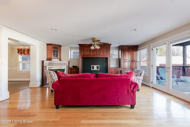 living room with light wood-style floors, a fireplace, and baseboards