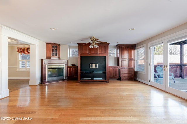 unfurnished living room featuring recessed lighting, a glass covered fireplace, and light wood-style floors