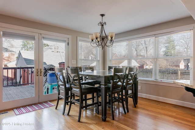 dining space with baseboards, french doors, wood finished floors, and an inviting chandelier