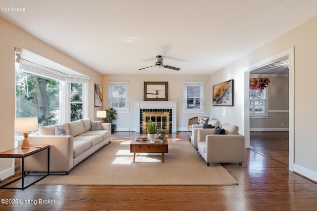 living room featuring a fireplace, baseboards, dark wood finished floors, and a ceiling fan