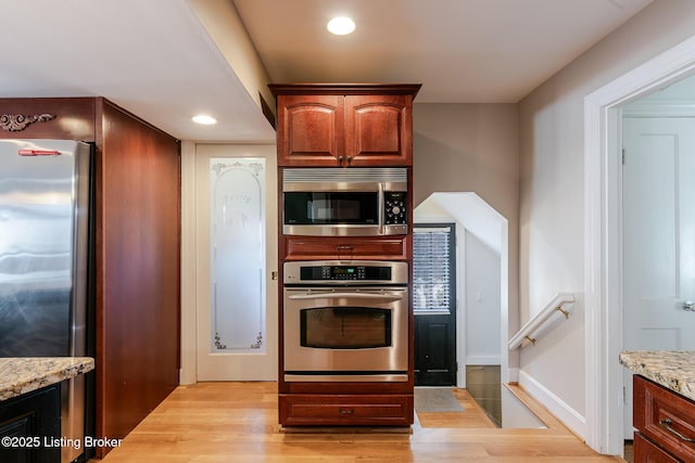 kitchen featuring stainless steel appliances, recessed lighting, light wood finished floors, and light stone counters