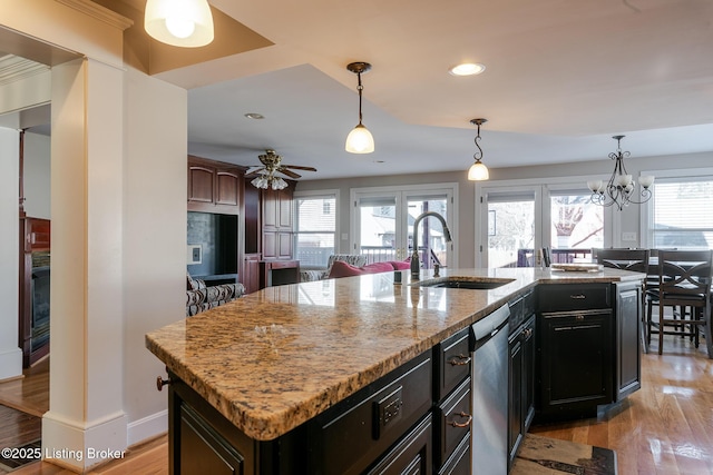 kitchen with open floor plan, an island with sink, a sink, and decorative light fixtures