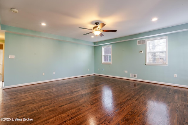 unfurnished room with dark wood-style flooring, visible vents, plenty of natural light, and baseboards