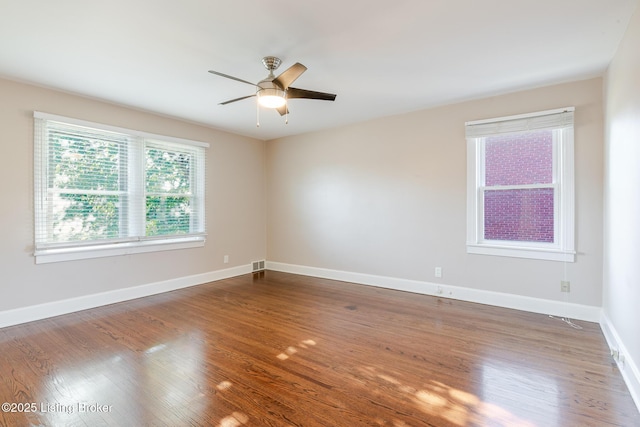 unfurnished room with baseboards, visible vents, ceiling fan, and dark wood-style flooring