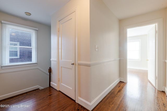 hall featuring dark wood-style flooring and baseboards