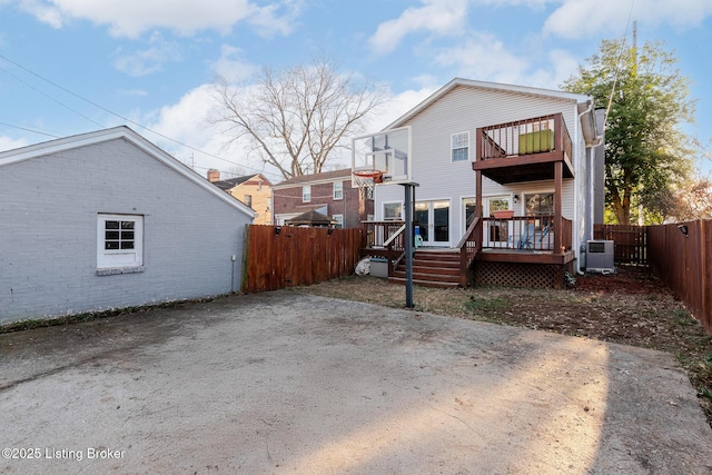 back of property with a deck, central AC unit, a fenced backyard, a balcony, and brick siding