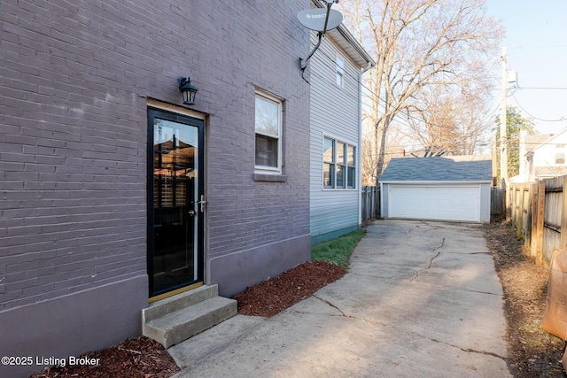 property entrance with brick siding, a detached garage, and fence