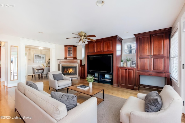 living room with a ceiling fan, a lit fireplace, light wood-style flooring, and recessed lighting