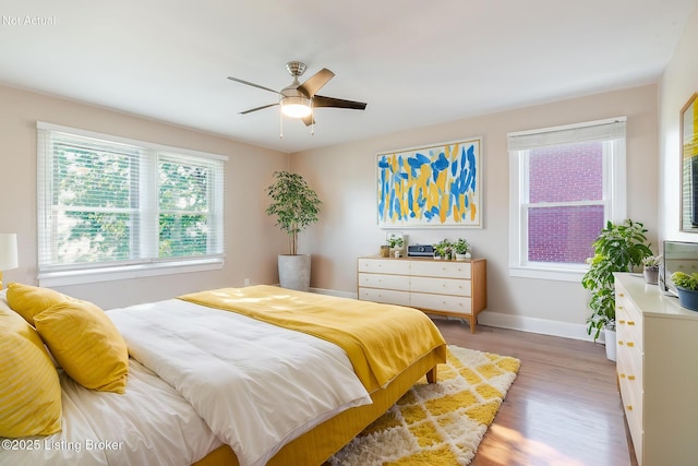 bedroom with ceiling fan, wood finished floors, and baseboards