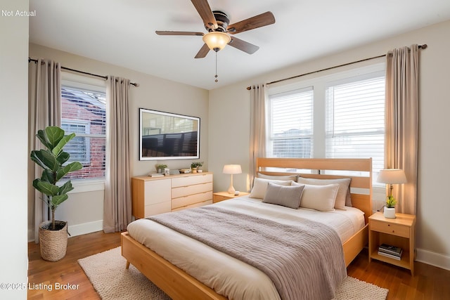 bedroom with multiple windows, wood finished floors, and baseboards