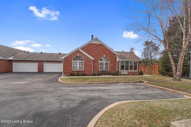 ranch-style house featuring brick siding, fence, a garage, driveway, and a front lawn