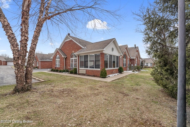 view of home's exterior featuring a sunroom, a yard, a chimney, and brick siding