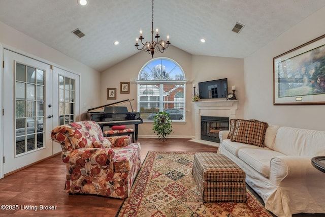 living room featuring a fireplace with flush hearth, lofted ceiling, visible vents, and wood finished floors