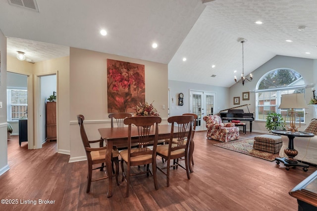 dining room featuring a textured ceiling, wood finished floors, visible vents, vaulted ceiling, and french doors