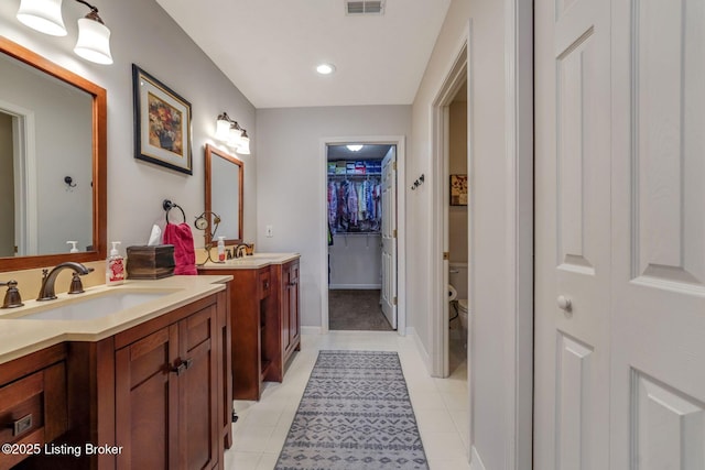 full bath with toilet, two vanities, a sink, and tile patterned floors