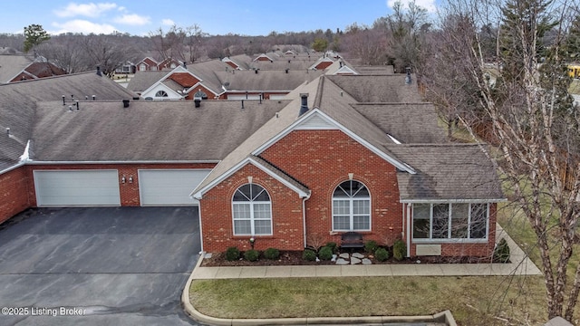 traditional-style house featuring aphalt driveway, brick siding, and a shingled roof