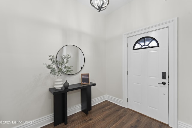 entryway with a chandelier, dark wood-style flooring, and baseboards