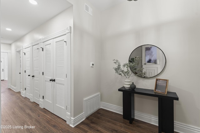 hallway featuring dark wood-style floors, recessed lighting, visible vents, and baseboards