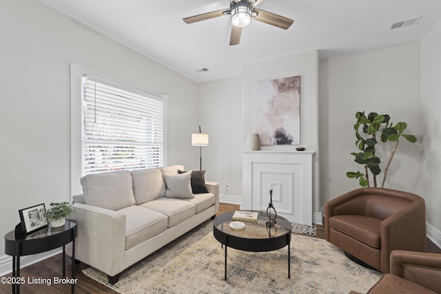 living area with a ceiling fan, baseboards, visible vents, and wood finished floors