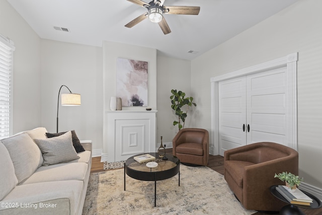 living room with light wood-style flooring, visible vents, and a ceiling fan