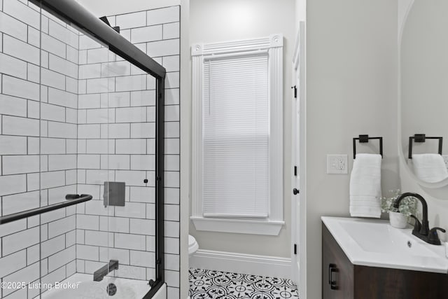 bathroom featuring baseboards, toilet, tile patterned flooring, combined bath / shower with glass door, and vanity