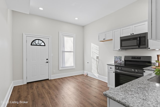 kitchen featuring light stone counters, stainless steel appliances, dark wood-type flooring, white cabinetry, and baseboards