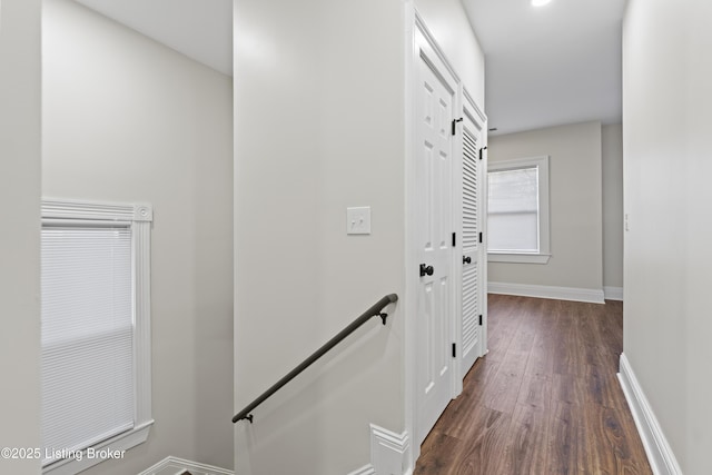 hall with baseboards, dark wood finished floors, and an upstairs landing