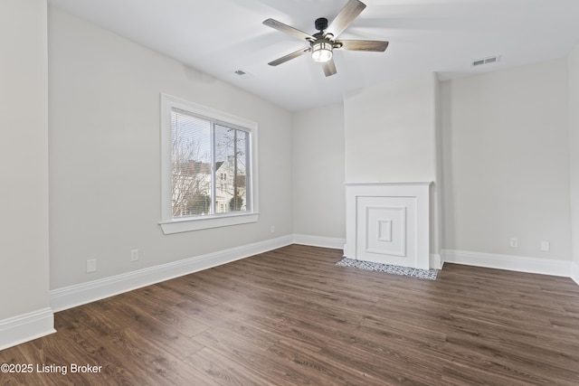 spare room featuring dark wood-style flooring, a ceiling fan, and baseboards