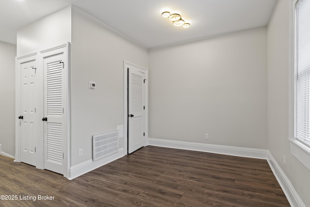 interior space featuring multiple closets, dark wood finished floors, visible vents, and baseboards