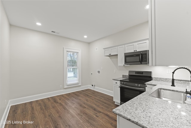 kitchen with stainless steel appliances, white cabinets, a sink, and light stone countertops