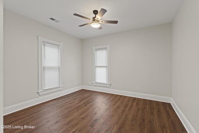 empty room with visible vents, dark wood finished floors, baseboards, and ceiling fan