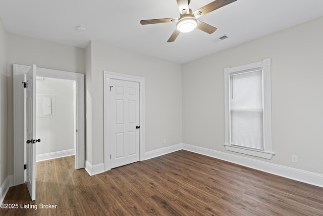 unfurnished bedroom with dark wood-style floors, baseboards, visible vents, and ceiling fan