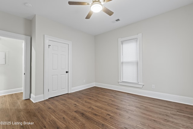 unfurnished room featuring dark wood-type flooring, visible vents, baseboards, and a ceiling fan