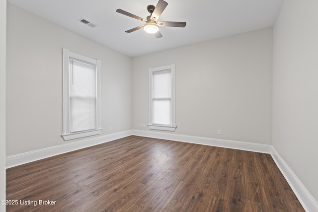 unfurnished room with ceiling fan, baseboards, visible vents, and dark wood finished floors