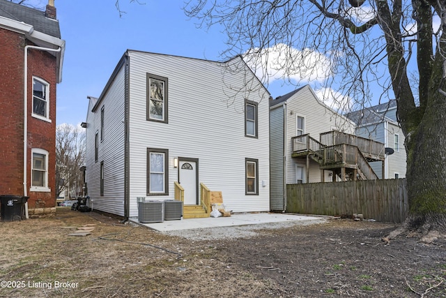 rear view of house featuring entry steps, central AC, and fence