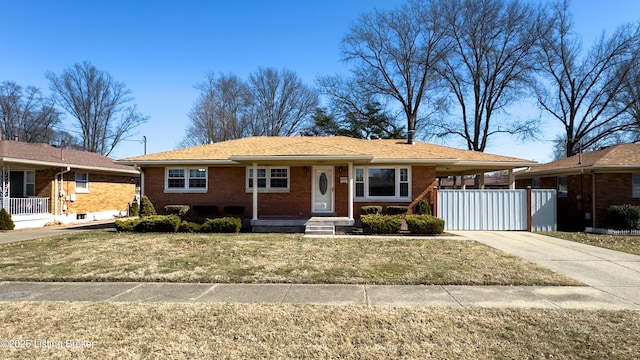 ranch-style home featuring an attached carport, concrete driveway, brick siding, and a front lawn