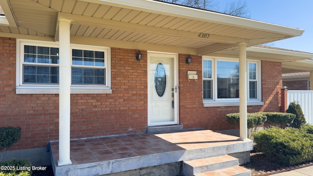 property entrance with covered porch and brick siding