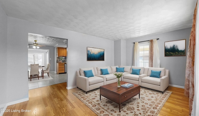 living room with light wood finished floors, plenty of natural light, baseboards, and a textured ceiling