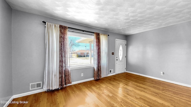 interior space featuring light wood-type flooring, visible vents, and baseboards