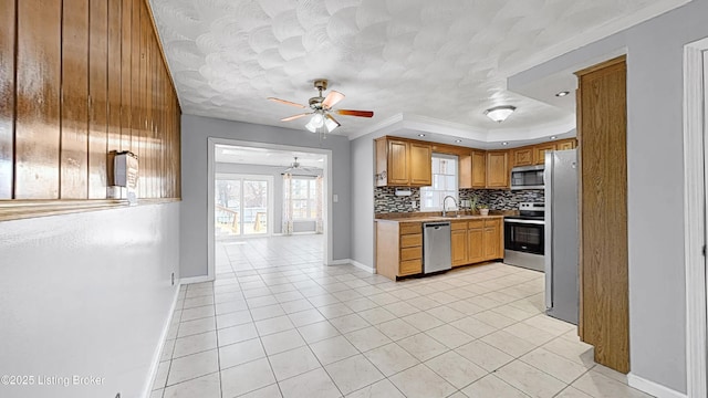 kitchen featuring light tile patterned flooring, stainless steel appliances, a sink, backsplash, and a raised ceiling