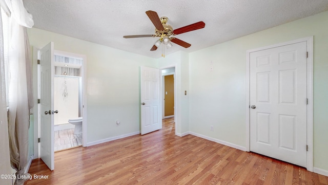 unfurnished bedroom with light wood-style floors, a textured ceiling, and baseboards