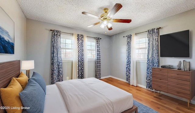 bedroom with a textured ceiling, wood finished floors, a ceiling fan, and baseboards